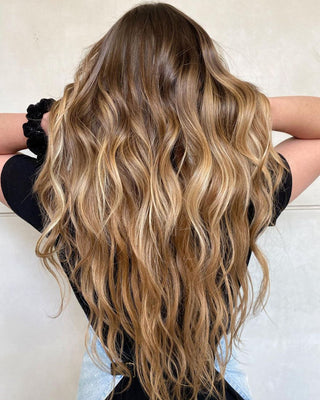 Woman with long wavy hair showcasing brazilian balayage highlights