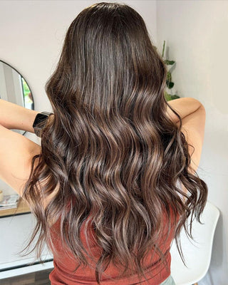 A woman with glamorous, long, Glam Seamless espresso-colored hair extensions.