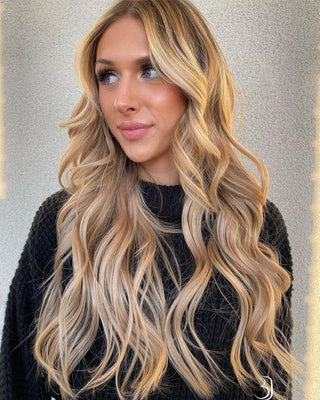 A woman with long, wavy hair enhanced by hair extensions, showcasing a vibrant and stylish appearance.